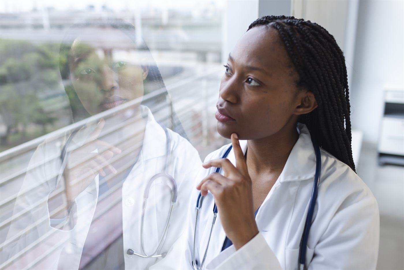 A thoughtful nurse looking out a hospital window